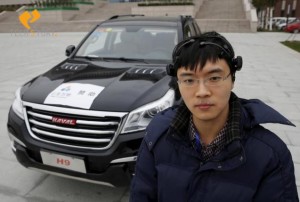 Researcher Zhang Zhao wearing a brain signal-reading equipment poses with a vehicle which can be controlled with his brain wave