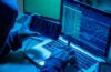 Hacker with computers in dark room