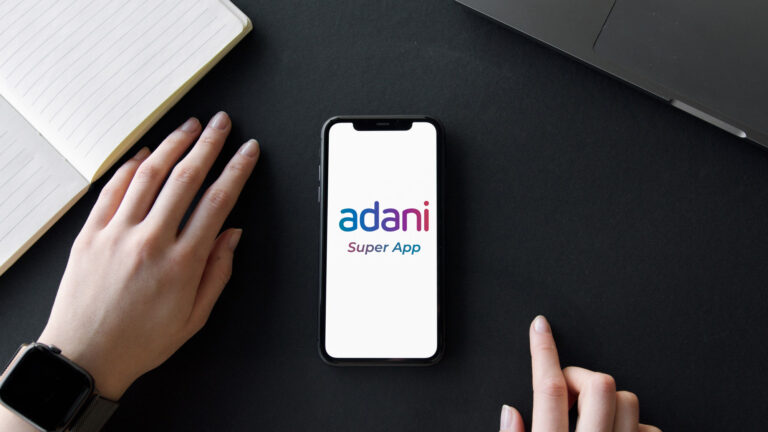 iPhone 11 placed on a table with Adani Super App mockup logo