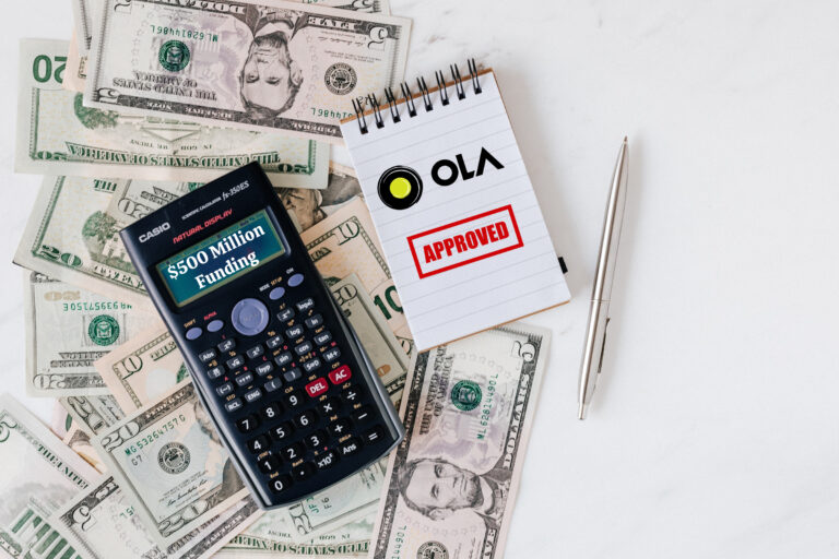 Ola Logo, Calculator and notepad placed over stack of USA dollars