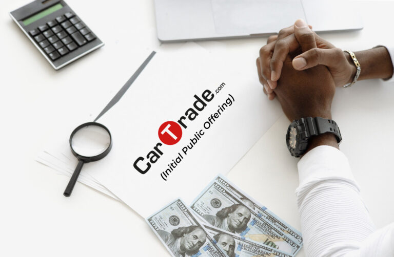 Image representing a Person's hands, pen, glass and a paper representing CarTrade IPO