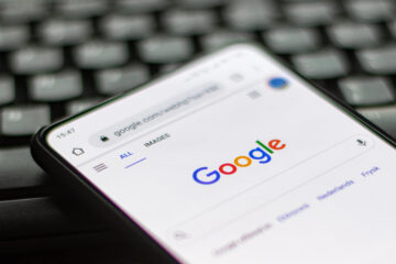 Google closeup logo displayed on a phone screen, smartphone on a keyboard is seen in this multiple exposure illustration, the company's symbol is globally recognized
