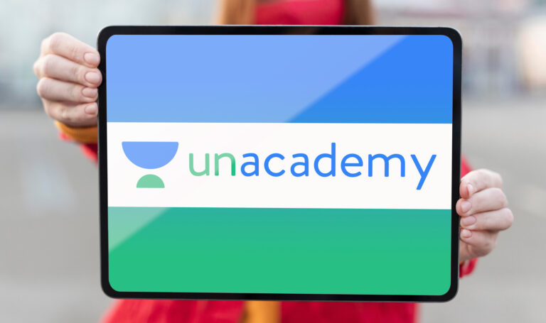 woman holding a tablet displaying Unacademy logo