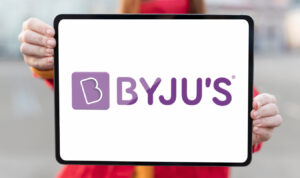 Byju’s logo displayed on a tablet held by Redhead woman