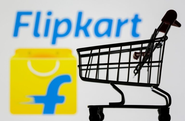 Small toy shopping cart is seen in front of displayed Flipkart logo in this illustration