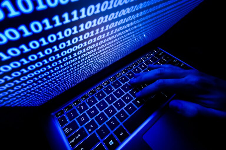 A hand on the keyboard is seen with binary code displayed on a laptop screen in this illustration photo