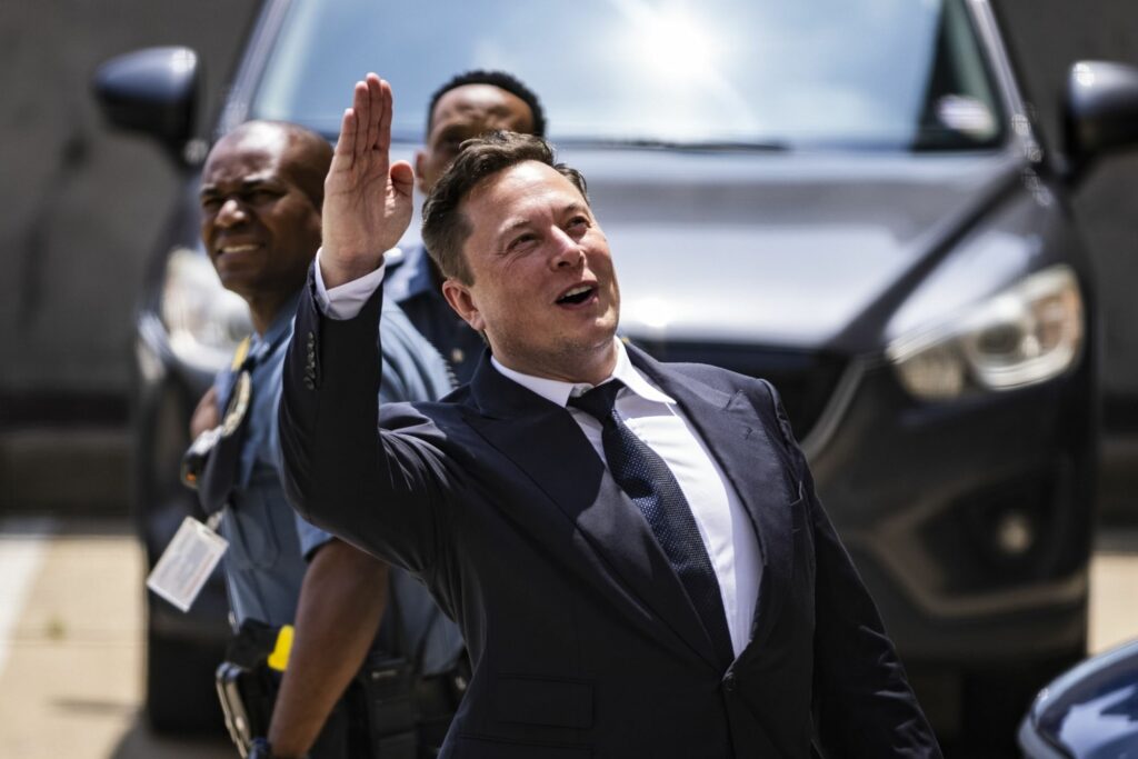 Elon Musk, chief executive officer of Tesla Inc., waves while departing court