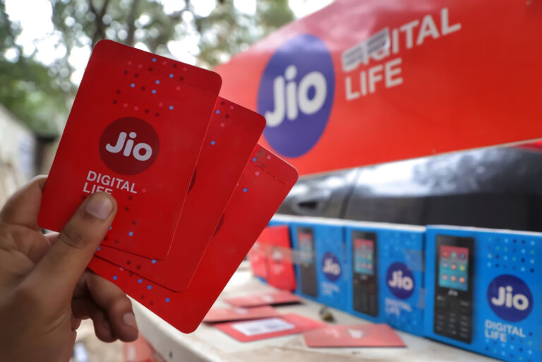 A customer holds new SIM cards of Reliance Jio mobile services at a Jio outlet