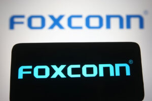 Dalam ilustrasi foto ini terlihat logo Foxconn dari produsen elektronik multinasional Taiwan di layar smartphone dan komputer.