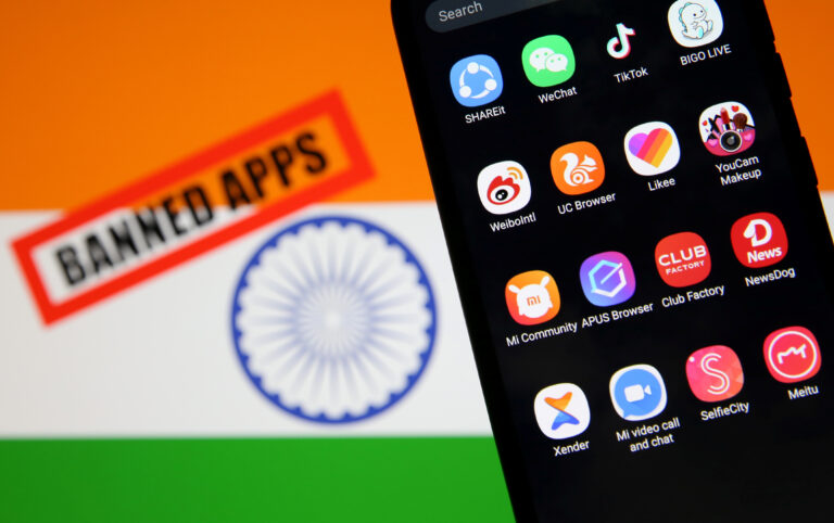 Smartphone with Chinese applications is seen in front of a displayed Indian flag and a "Banned app" sign