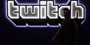 A person standing in front of an illuminated banner of Twitch