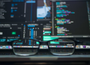 Image of a pair of glasses with a background of computer screens with codes