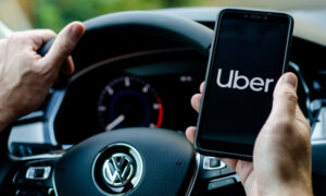 A phone screen depicting the Uber logo alongside the steering wheel of a Volkswagen car