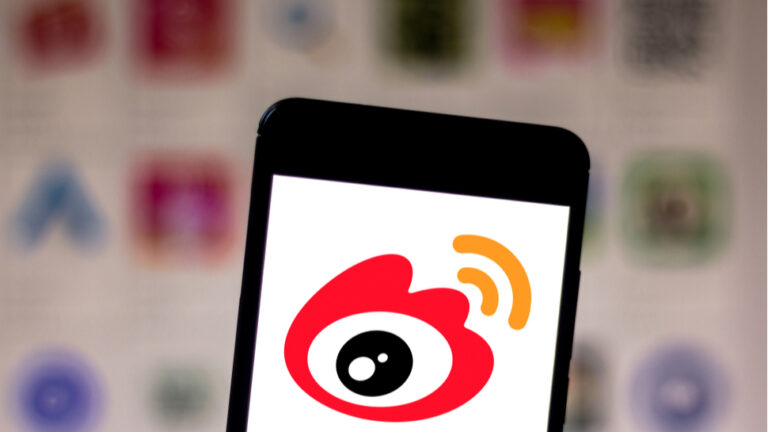 Weibo logo shown on a phone screen with a blurred background