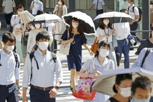 People walk with parasols in Tokyo as the temperature rises on June 26