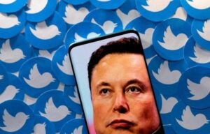 An image of Elon Musk is seen on smartphone placed on printed Twitter logos in this picture illustration