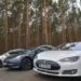 Tesla electric vehicles stand on a road on the edge of a forest where the construction of a Tesla factory is planned.