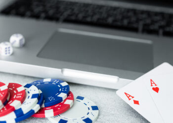 Cocnept of poker online games, chips and cards with laptop on grey background.