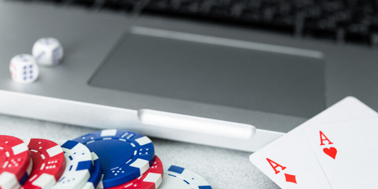 Cocnept of poker online games, chips and cards with laptop on grey background.