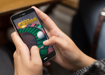 gambling concept: girl using a digital generated phone with online casino on the screen. All screen graphics are made up.