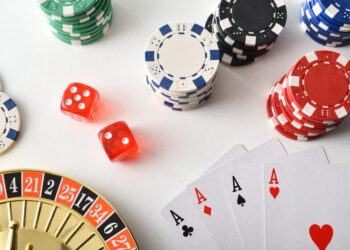 Casino games background isolated on white table with playing cards, betting chips and dice for playing various games of chance. Top view.