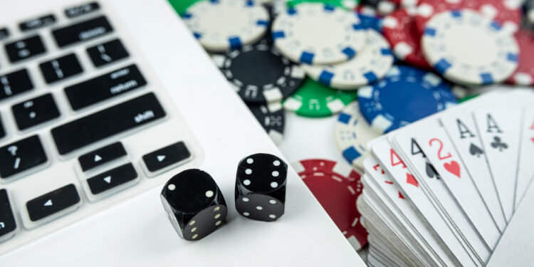 Online poker with laptop playing card chips and dice. Online gambling casino concept