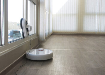 White robotic vacuum cleaner and robot window cleaner work together. Smart cleaning technology.