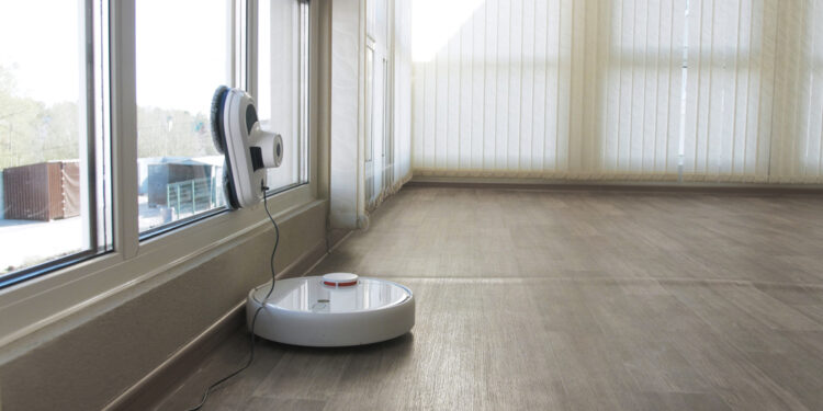 White robotic vacuum cleaner and robot window cleaner work together. Smart cleaning technology.