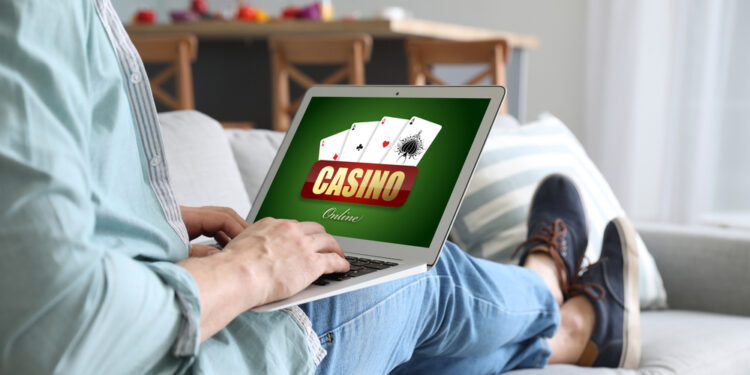 Young man with laptop playing in casino online at home