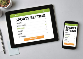 Sports betting concept on tablet and smartphone screen over gray table. All screen content is designed by me. Flat lay