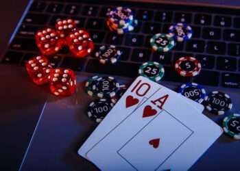 Casino play online theme. Playing chips, cards and dices on laptop close-up.