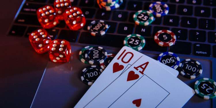 Casino play online theme. Playing chips, cards and dices on laptop close-up.